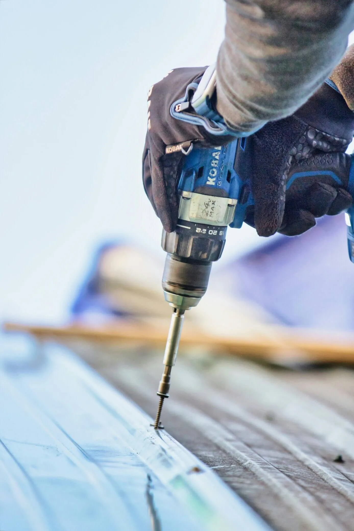 Roofer fastening metal roofing with a power drill
